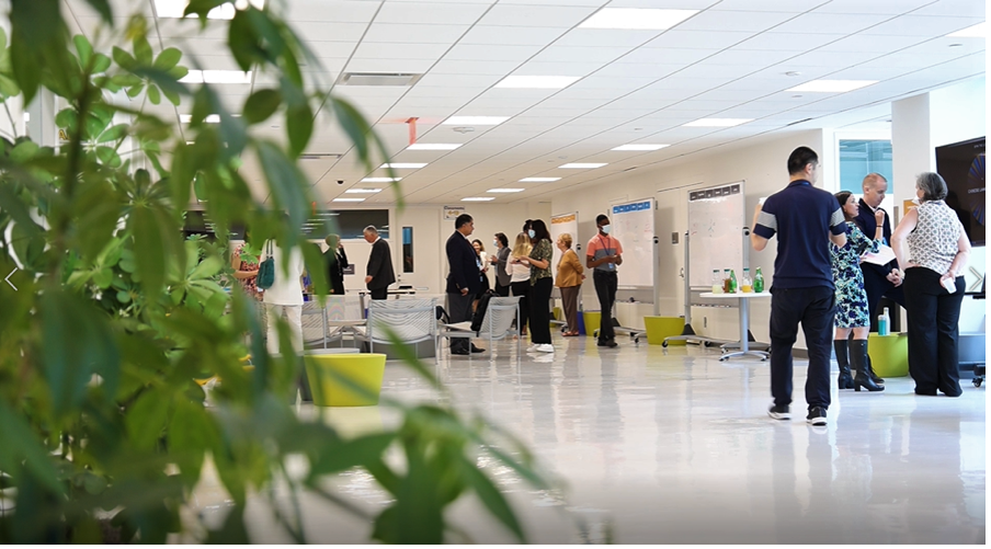 A group of people stands in a hallway adorned with various plants, creating a vibrant and inviting atmosphere.