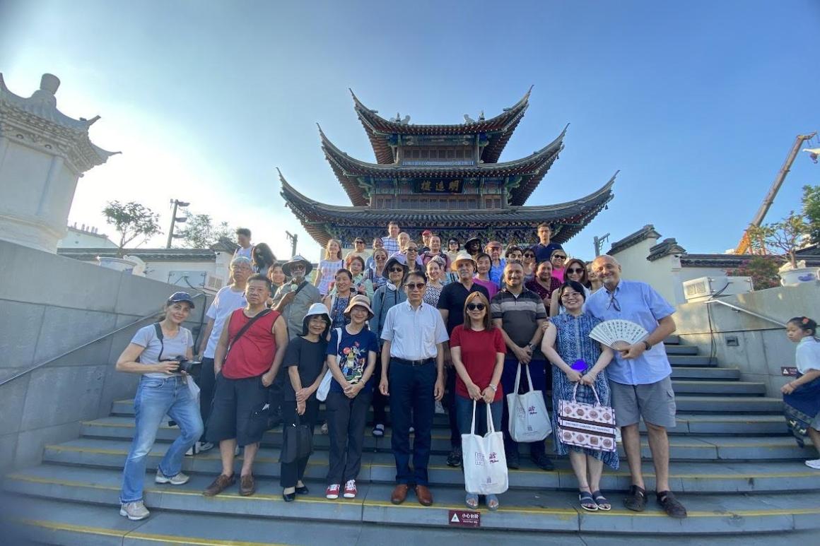 A diverse group of individuals smiling and posing together in front of a traditional pagoda structure.